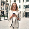 Frau in der Stadt die am Smartphone nach Immobilien Trends sucht