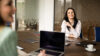 Zwei Frauen sitzen mit Laptop und Tablet an einem Meetingtisch